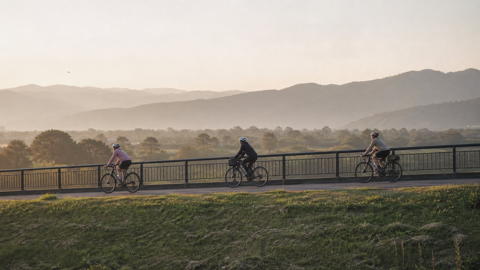 Riders crossing a riverside bridge in the morning light